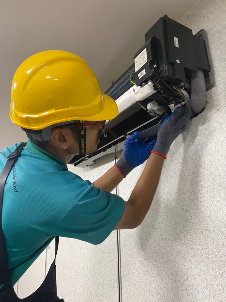 a man wearing a hard hat and gloves working on a air conditioner